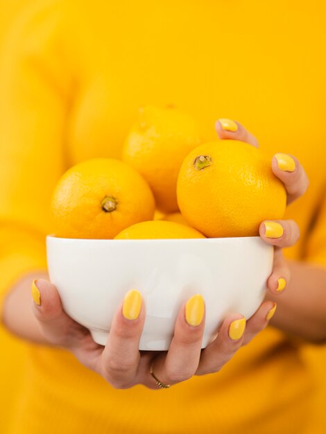 Mujer sosteniendo tazón de limones