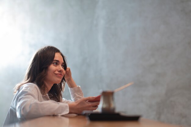 Mujer sosteniendo teléfono con cafetera defocused