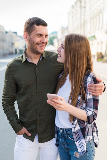 Mujer sosteniendo teléfono celular y mirando a su novio en la calle