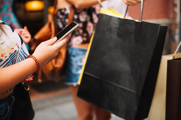 Mujer sosteniendo el teléfono cerca de bolsas de papel