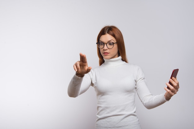 Mujer sosteniendo teléfono inteligente y presionando el botón virtual