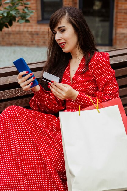 Mujer sosteniendo teléfono inteligente y tarjeta de crédito comprando en línea durante las ventas