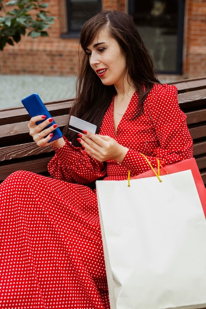 Mujer sosteniendo teléfono inteligente y tarjeta de crédito comprando en línea durante las ventas