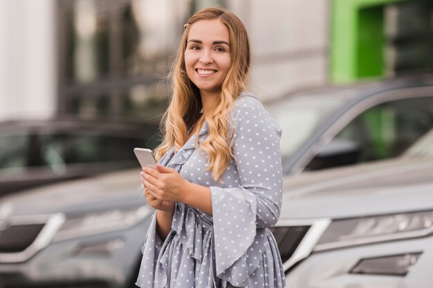 Mujer sosteniendo un teléfono y mirando al fotógrafo