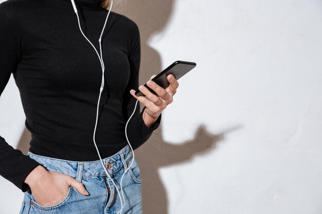 Mujer sosteniendo teléfono móvil con la mano en el bolsillo