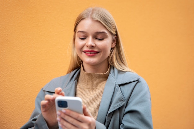 Mujer sosteniendo un teléfono de tiro medio