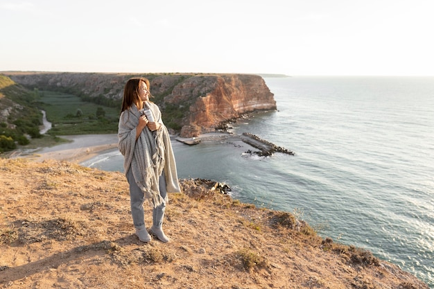 Mujer sosteniendo un termo mientras caminaba por la costa