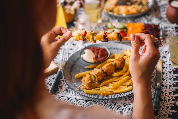 Mujer sosteniendo trozos de pollo en brochetas espolvoreadas con sésamo