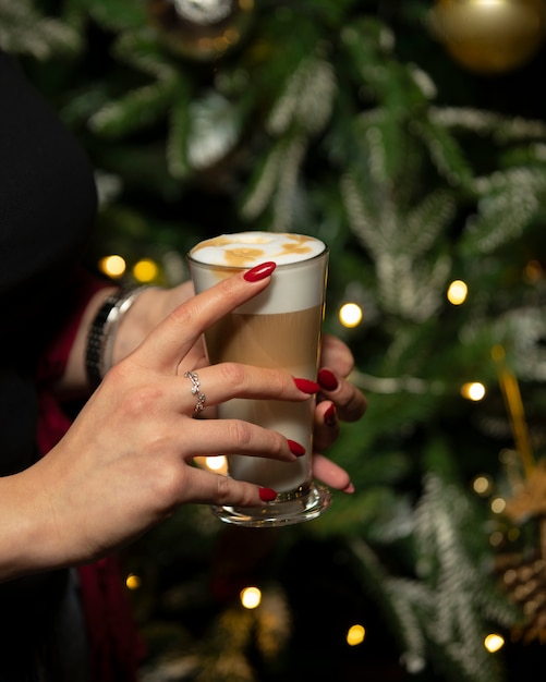 mujer sosteniendo un vaso de café con leche con espuma