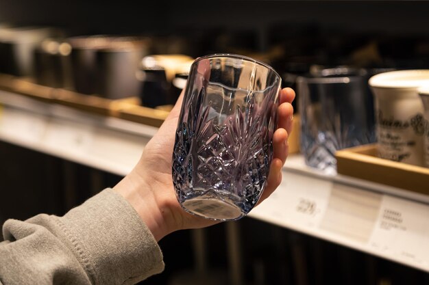 Mujer sosteniendo un vaso de un estante en una tienda de artículos para el hogar