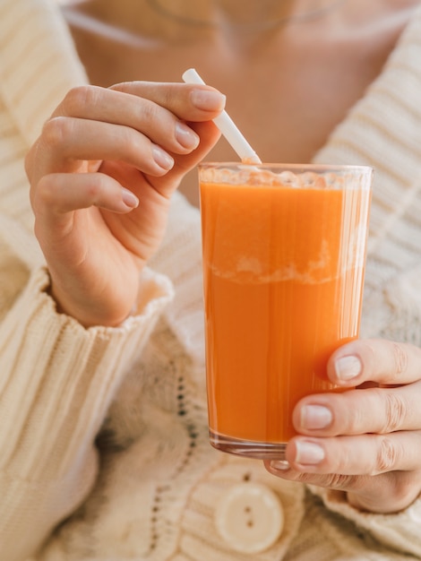 Mujer sosteniendo un vaso con jugo de zanahoria orgánico