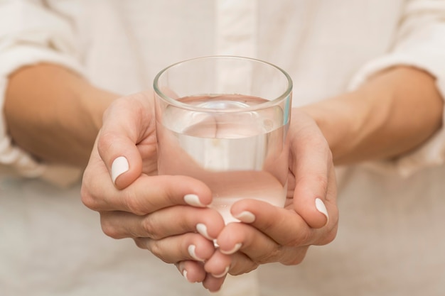 Mujer sosteniendo un vaso lleno de agua