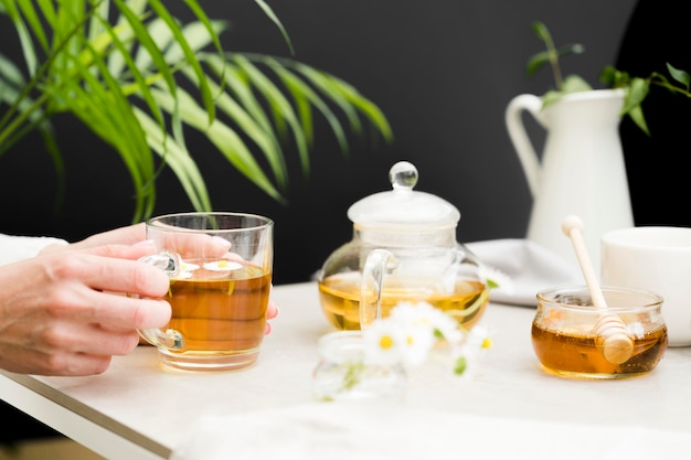 Mujer sosteniendo un vaso con té en la mesa