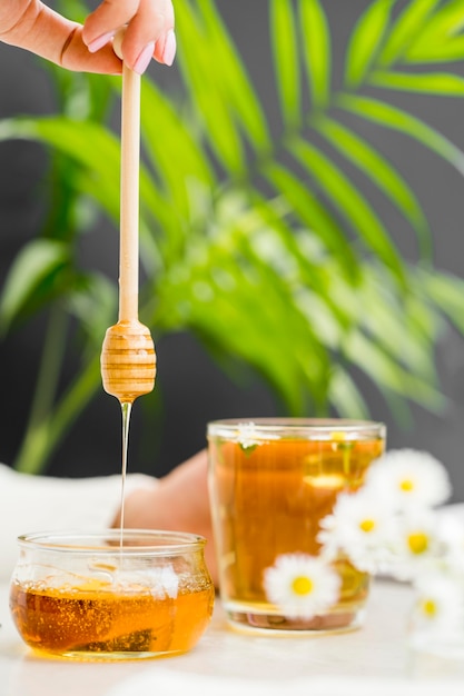 Mujer sosteniendo un vaso con té y miel cazo