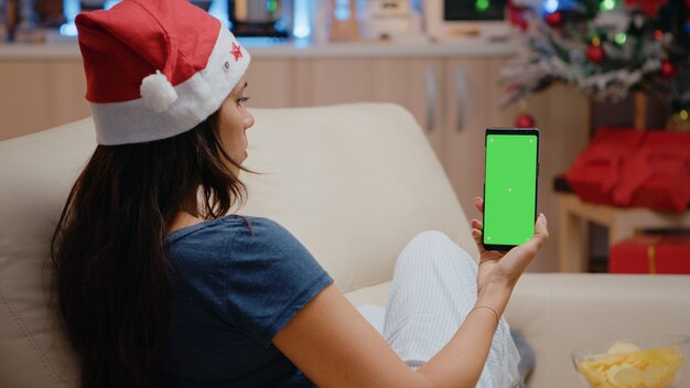 Mujer sosteniendo verticalmente smartphone con pantalla verde