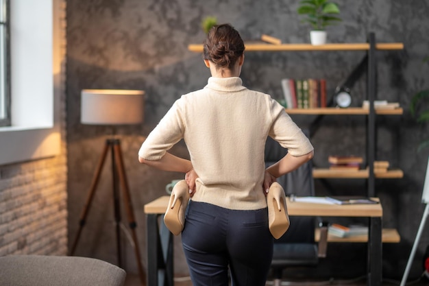 Mujer sosteniendo zapatos de tacón alto en sus manos