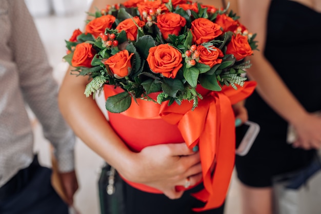 Mujer sostiene caja roja con rosas rojas