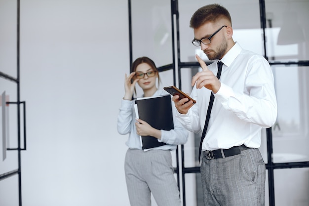 La mujer sostiene una carpeta. Socios de negocios en una reunión de negocios. Hombre usa el teléfono. Personas con gafas