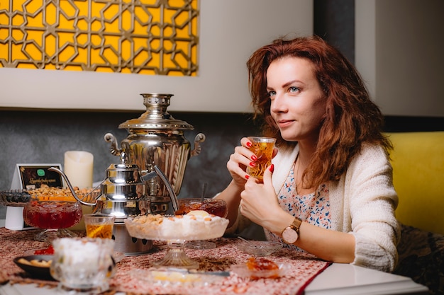 Mujer sostiene cristal armudu vidrio con té negro servido