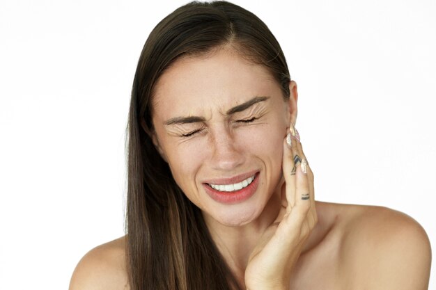 La mujer sostiene los dedos en su mejilla que muestra dolor de muelas