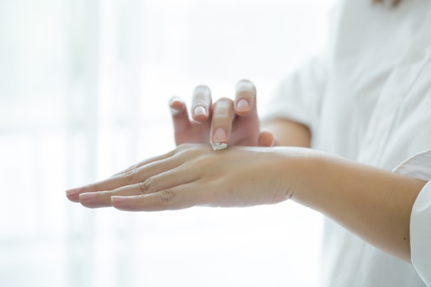 mujer sostiene un frasco con una crema cosmética en sus manos