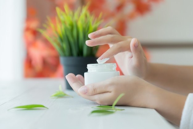 Mujer sostiene un frasco con una crema cosmética en sus manos