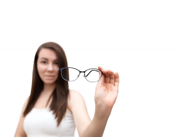 La mujer sostiene las lentes en la mano, aisladas sobre fondo blanco. Enfoque selectivo en anteojos.