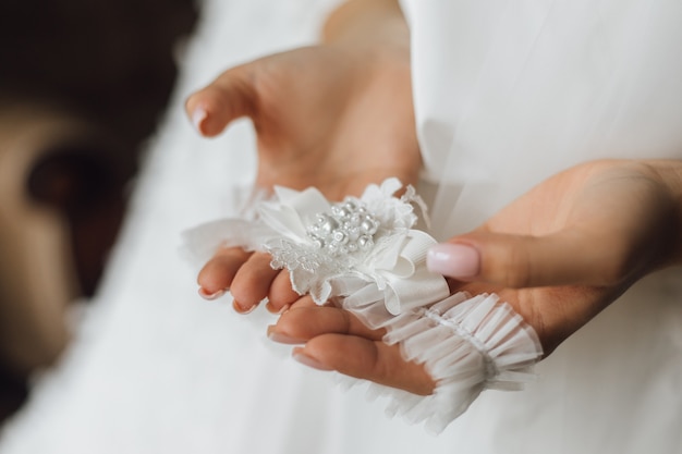 Mujer sostiene la liga de la boda, sin rostro.