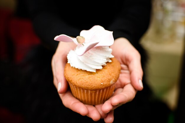 La mujer sostiene la magdalena con la flor del esmalte