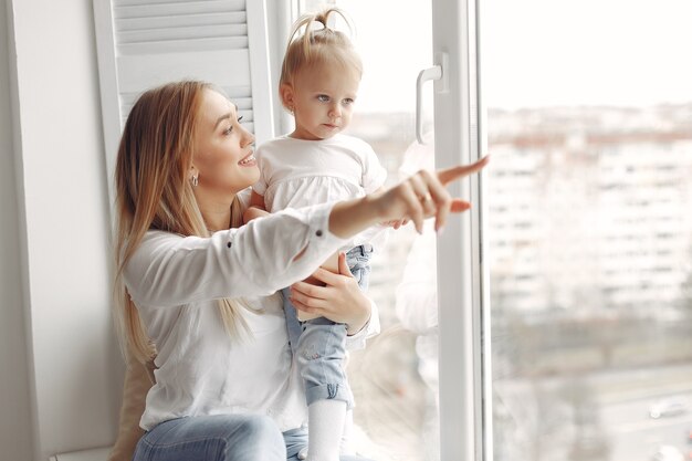 La mujer sostiene a un niño en sus brazos y la abraza. Madre con camisa blanca está jugando con su hija. La familia se divierte los fines de semana.