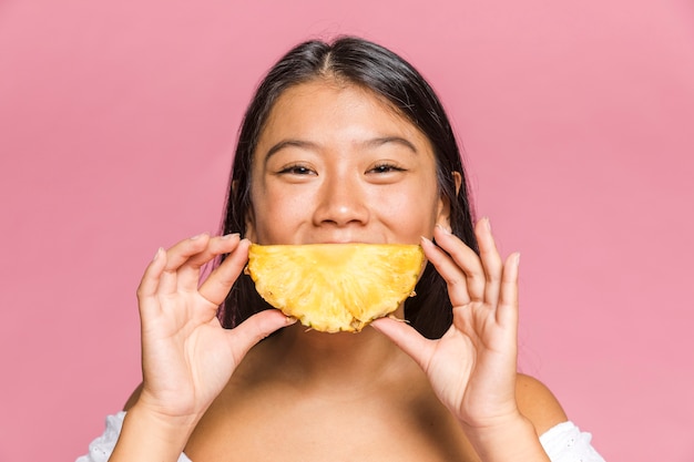 La mujer sostiene una piña como una forma sonriente