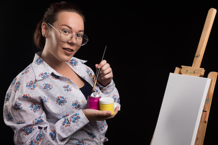 Foto gratuito mujer sostiene pincel y pinturas en negro