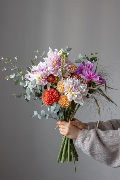 Una mujer sostiene un ramo festivo con flores de crisantemo en sus manos.