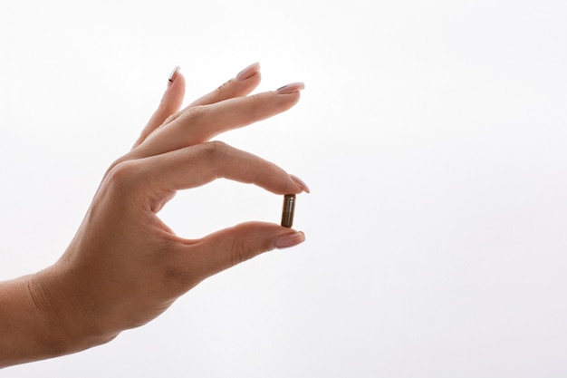 La mujer sostiene en su mano una cápsula con vitaminas o aceite