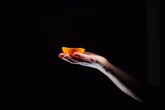 Mujer sostiene en su mano la mitad de una naranja