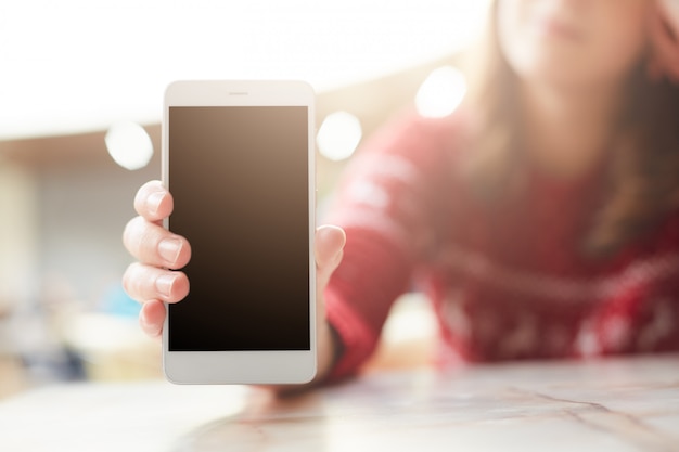 La mujer sostiene el teléfono inteligente blanco moderno