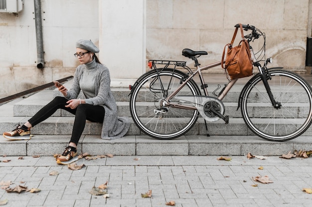 Foto gratuita mujer y su bicicleta sentados en las escaleras