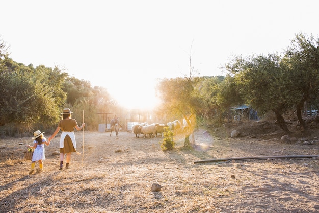 Mujer con su hija caminando en el campo con animales