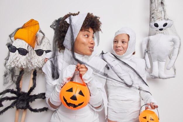 mujer y su hija fingen ser fantasmas sostiene calabazas prepararse para halloween mascarade se miran con alegría rodeadas de atributos hechos a mano. Vacaciones misteriosas de otoño