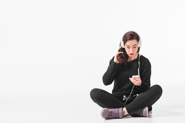 Mujer con su mano en el cabello escuchando música en auriculares a través de un reproductor de mp3