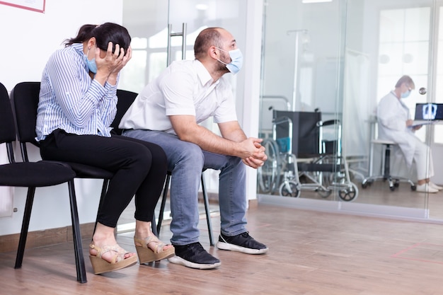 Mujer y su marido llorando en la sala de espera del hospital