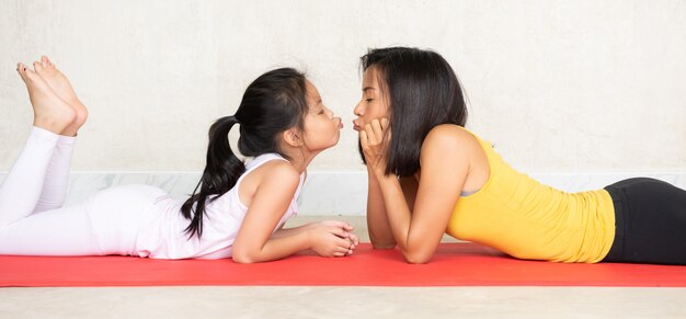 Mujer y su pequeña hija encantadora en estera de yoga