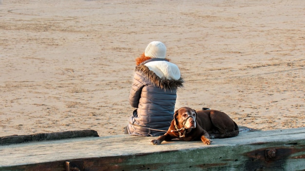 Mujer con su perro en la playa en liverpool reino unido
