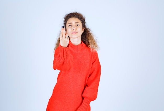 mujer en sudadera roja apuntando a algo.