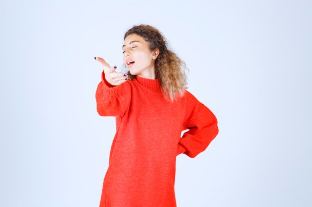 mujer en sudadera roja apuntando a alguien adelante.