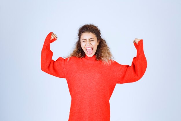 mujer en sudadera roja mostrando su puño y significando su poder.