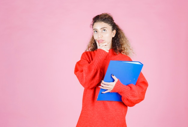 mujer en sudadera roja parece confundida y pensativa.