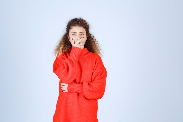 mujer en sudadera roja parece confundida y pensativa.