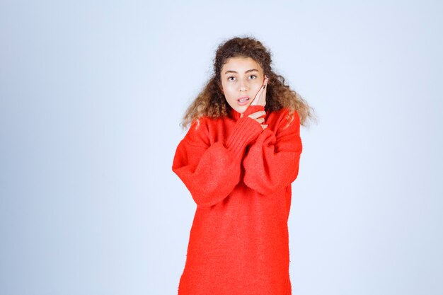 mujer en sudadera roja parece confundida y pensativa.