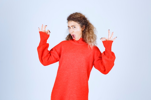 mujer en sudadera roja que muestra el signo de disfrute.